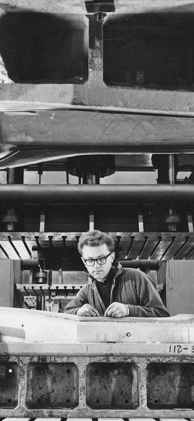 Black and white photograph of of a mechanic working on a Holden car