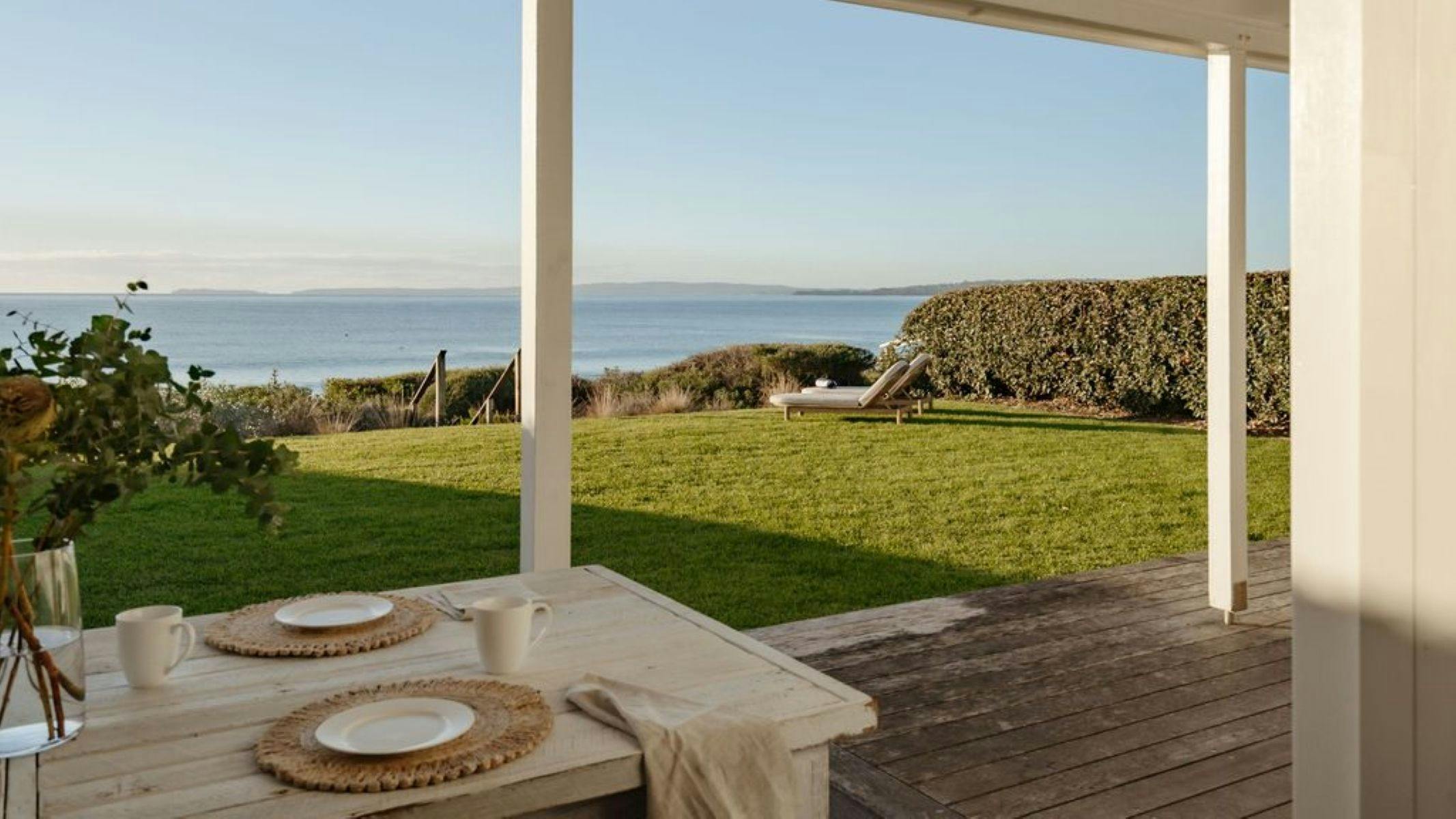 Image from the back deck looking out to the ocean on sunrise. Ocean is blue and still and sun is out