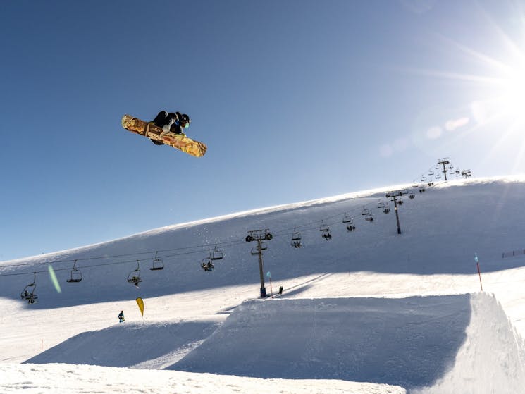 snowboarder in the air after a jump, chairlift in background