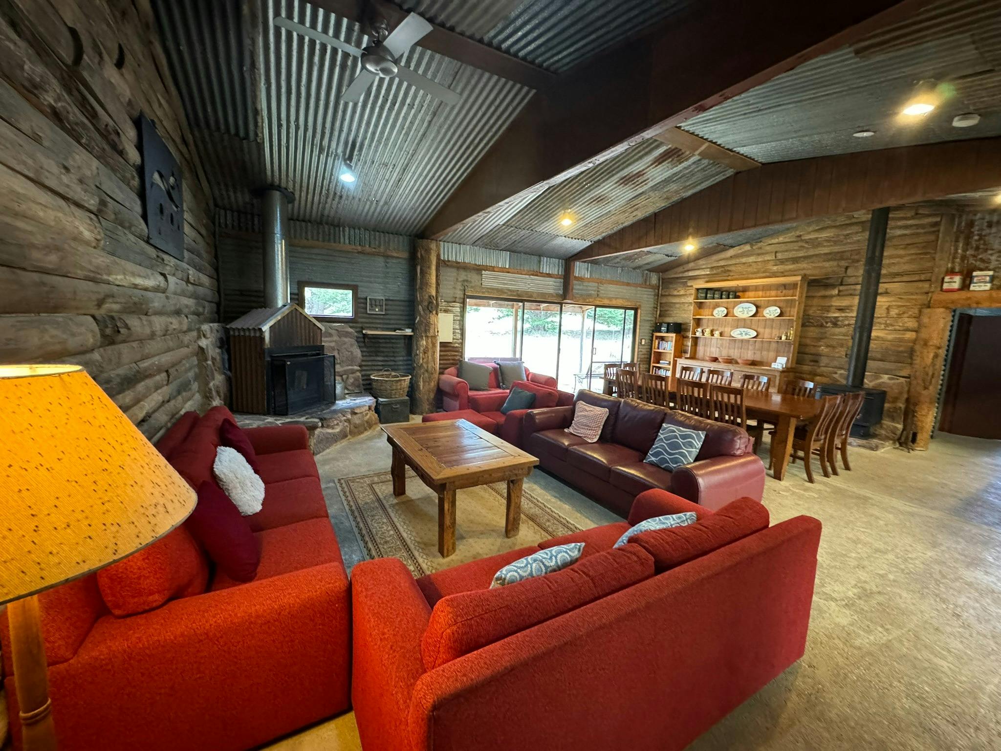 Comfortable sofas facing an open fire place and stone hearth and a large dining table and buffet