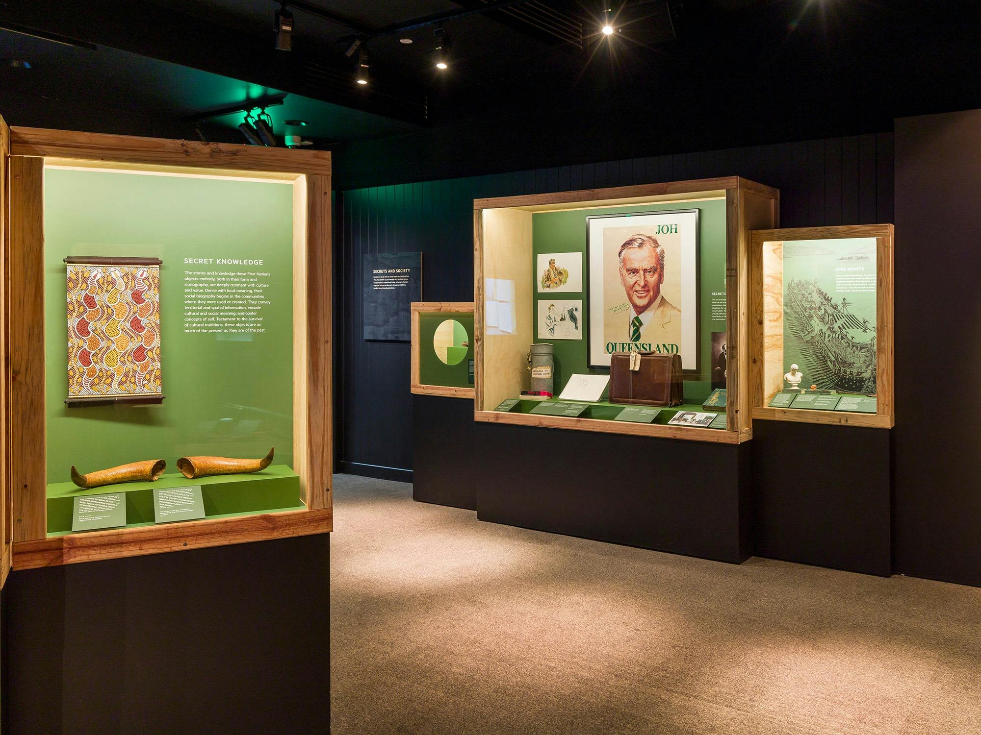 Dark museum exhibition room with displays from the Secrets: Objects of Intrigue Exhibition.