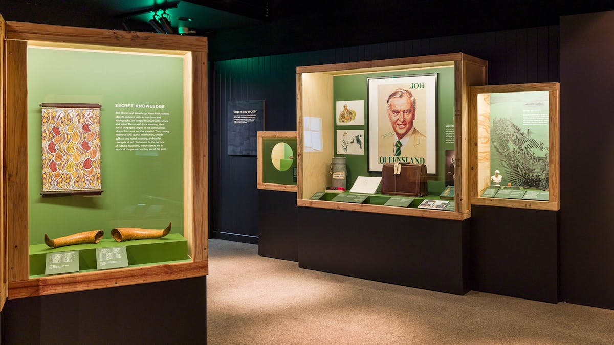 Dark museum exhibition room with displays from the Secrets: Objects of Intrigue Exhibition.