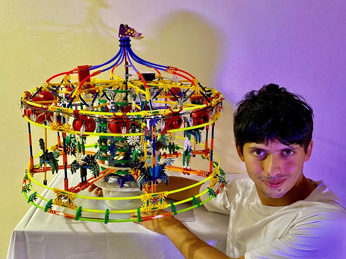 A person alongside a model of a merry-go-round
