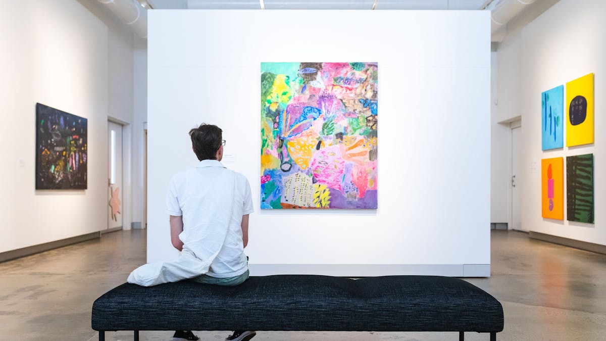Person sitting on seat in gallery space viewing artwork