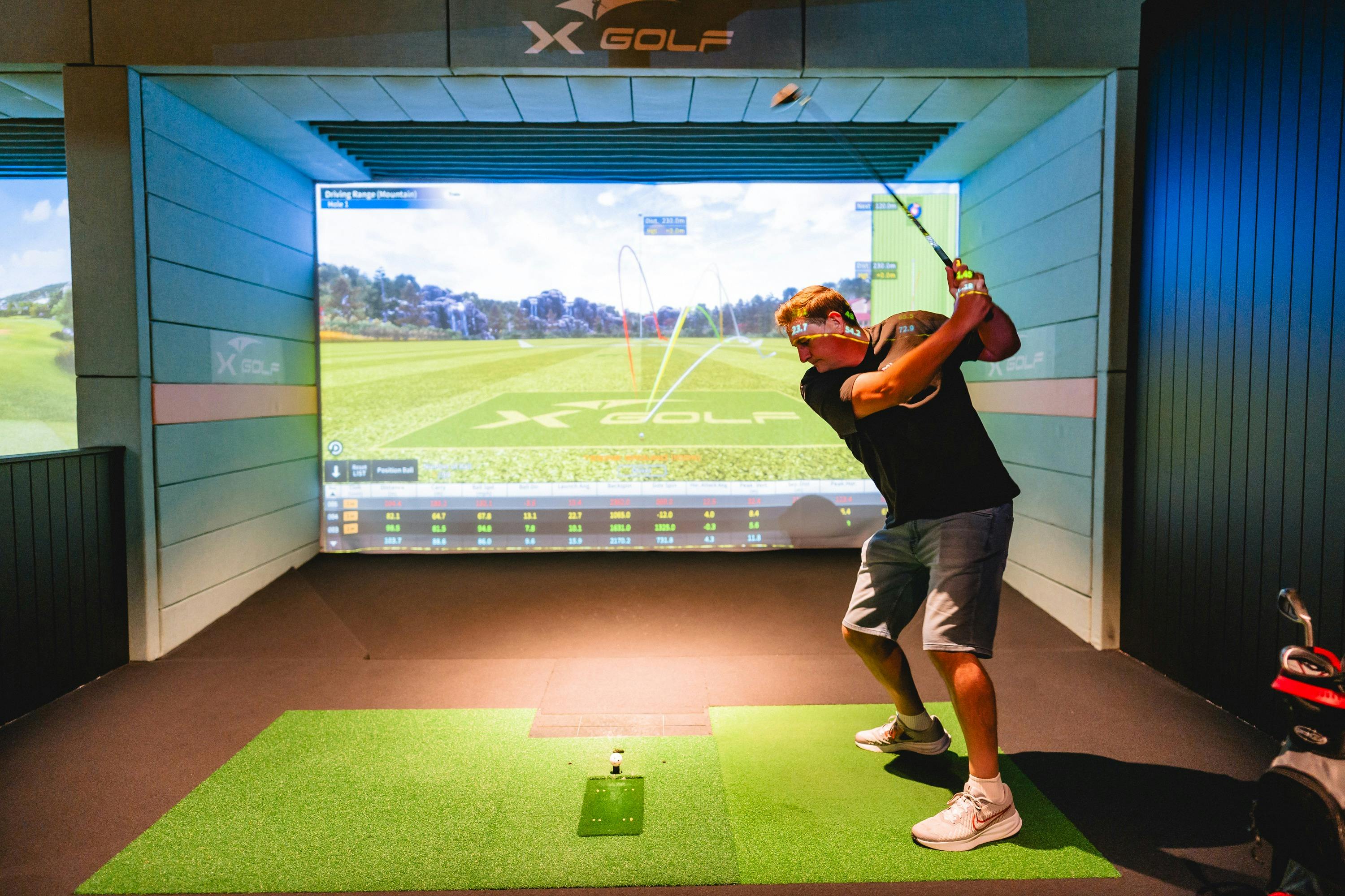 Man Swinging a Club at X-Golf Venue