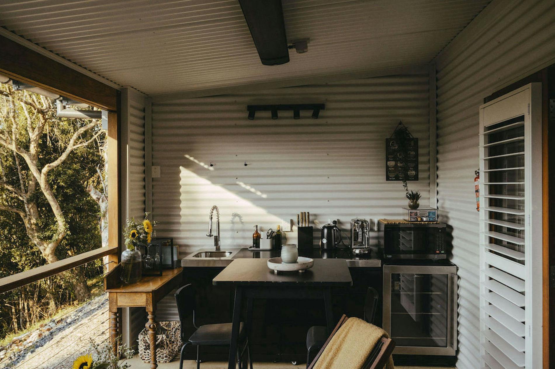 Outdoor kitchen featuring fridge, benchspace, a table and chairs and kitchen utilities