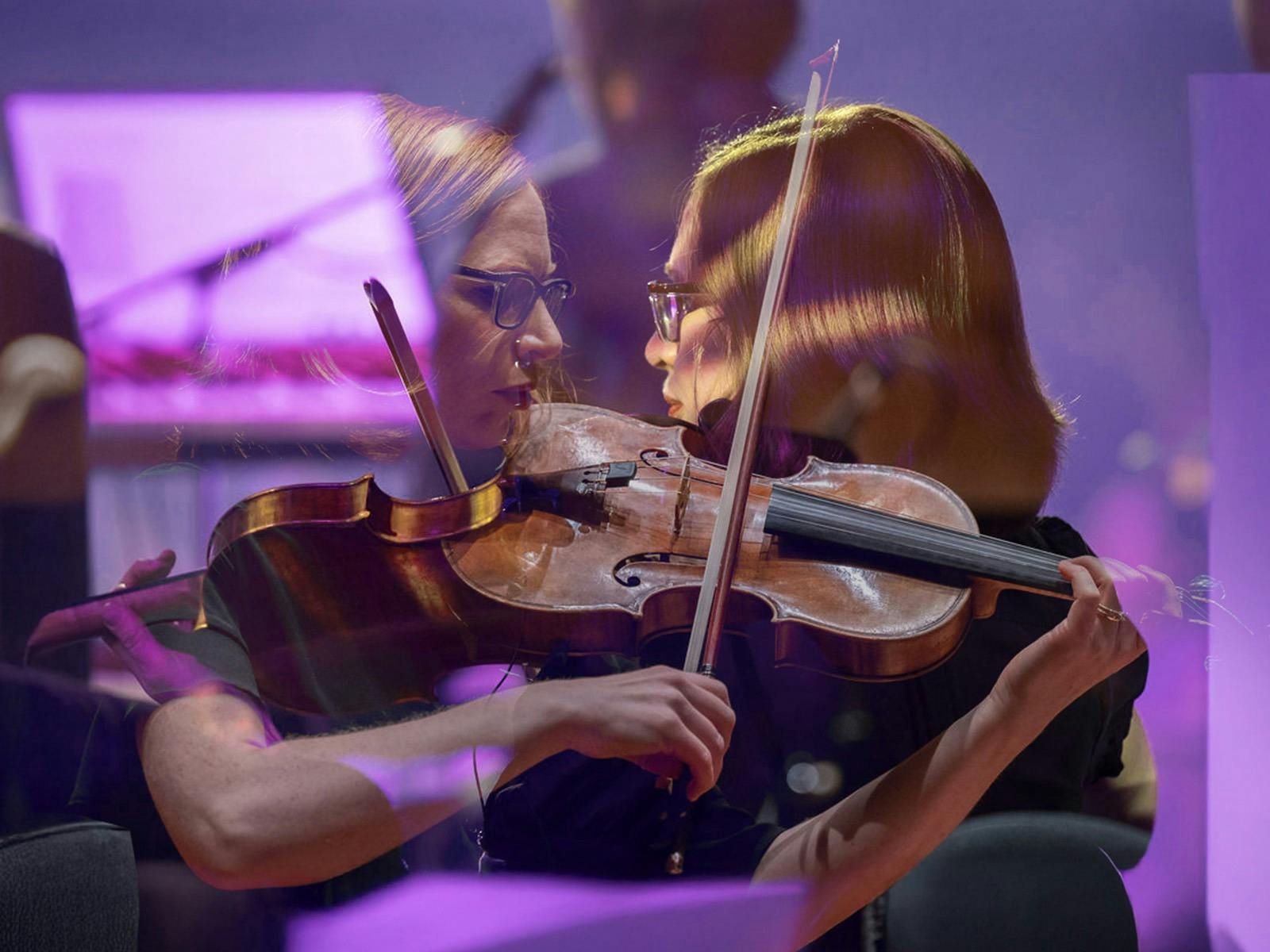 A layered image of a woman playing a violin, purple tones