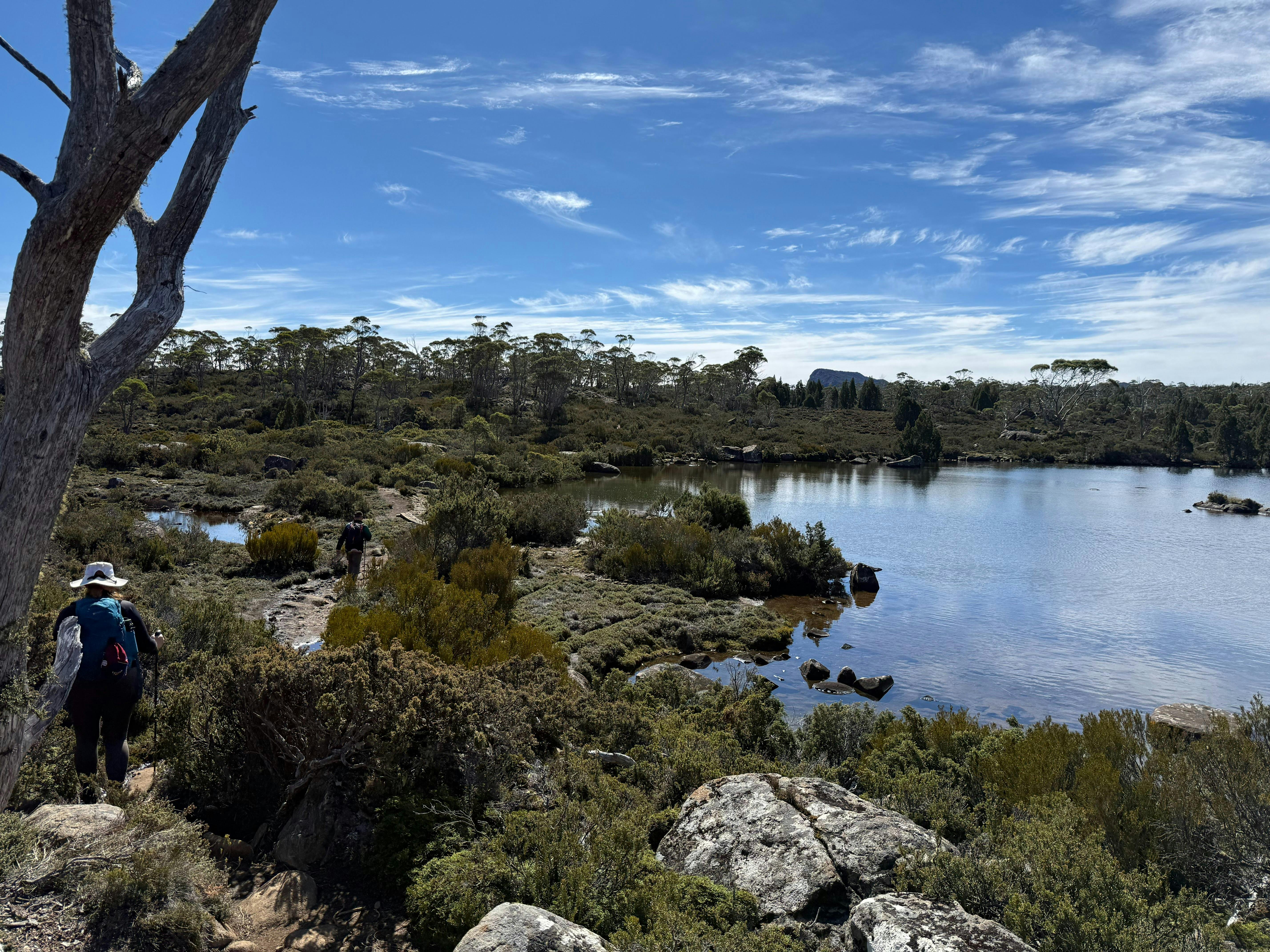 Walkers hiking beside alpine lake in Walls of Jerusalem National Park Tasmania.