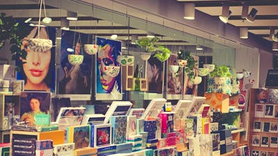 Posters of portraits from collection in the background with rows of boxed stationery