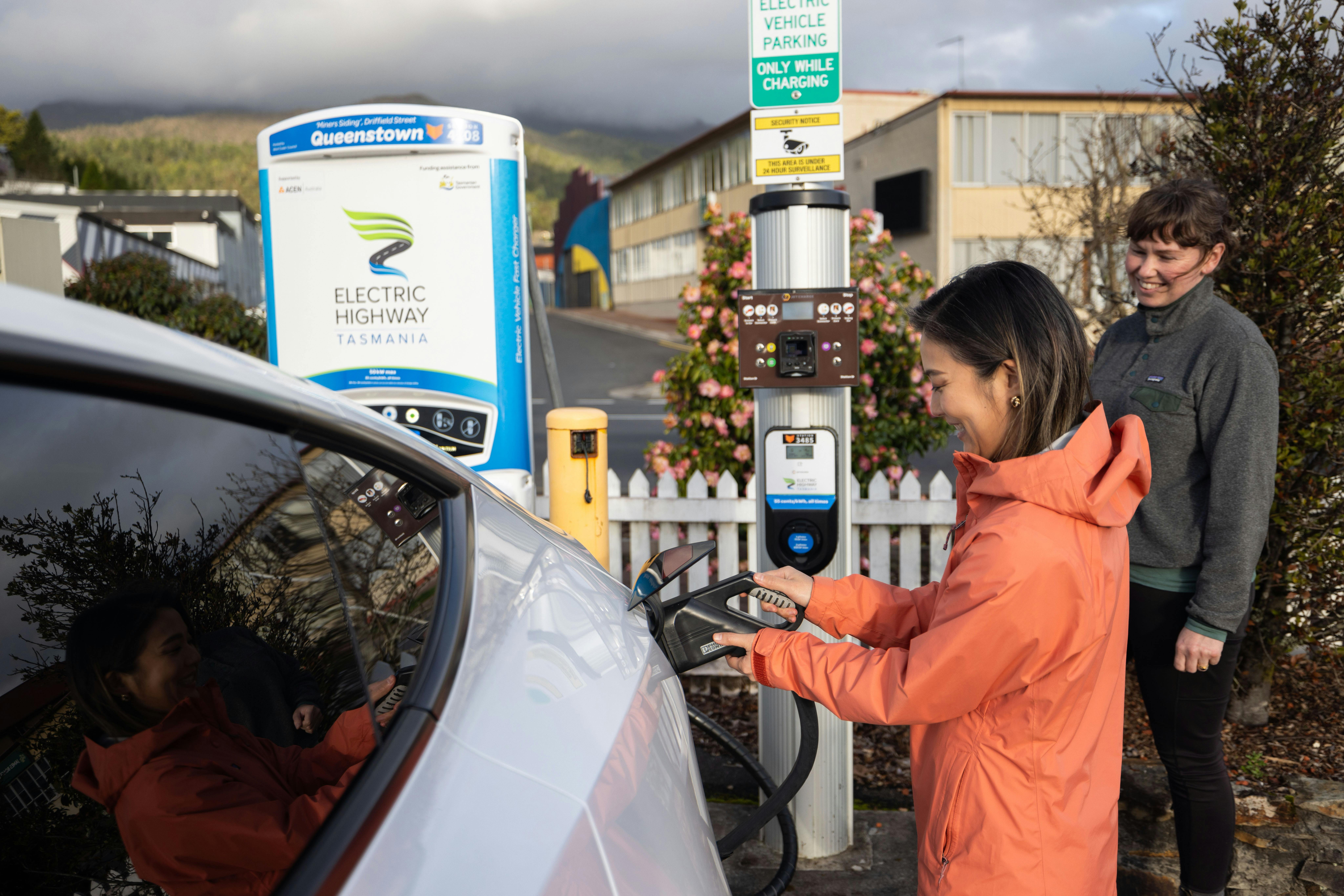 Tourist connecting an Electric Vehicle hire car (Tesla Model Y) to a public charging station.