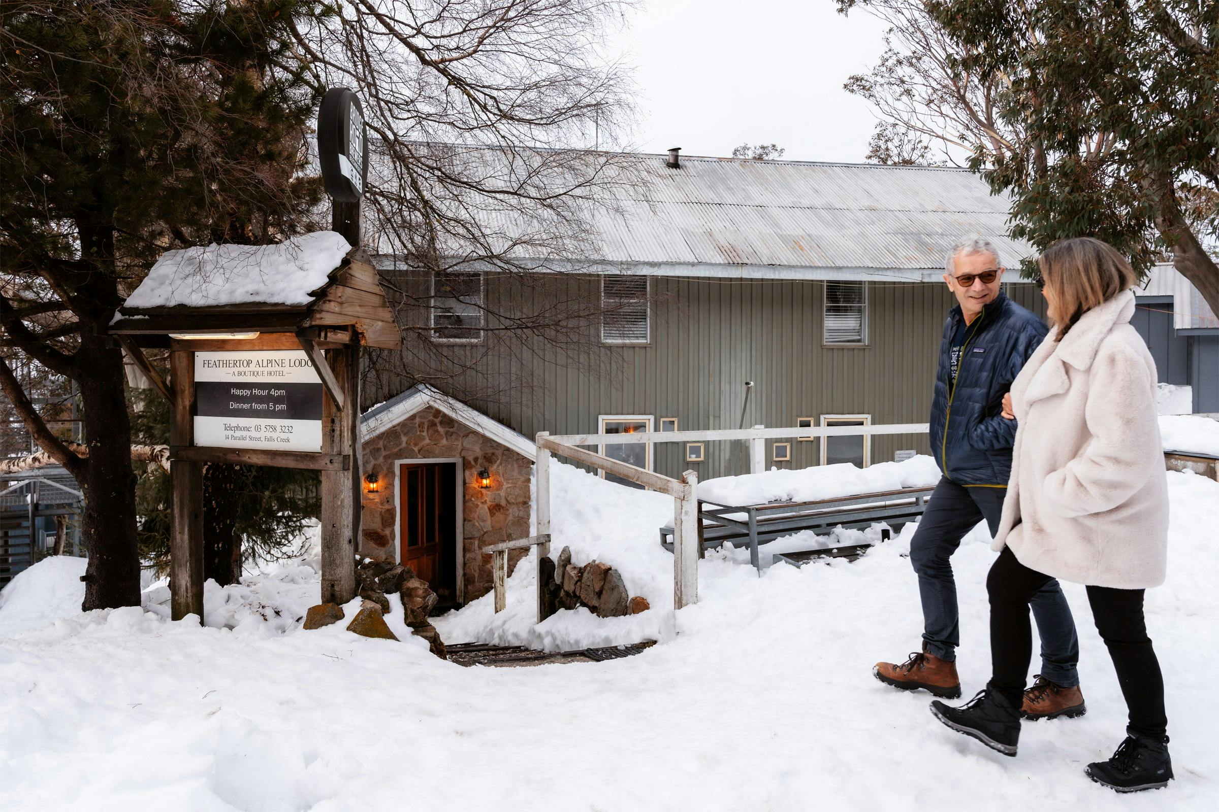 Snow falls as guests approach Feathertop’s warmly lit alpine entrance at Falls Creek.