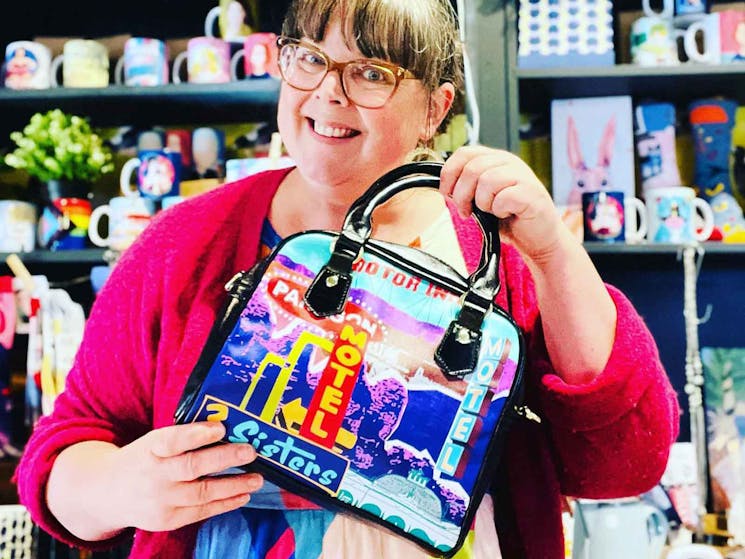 Kara holds our Retro Blue Mountains bowling bag at the shop counter.