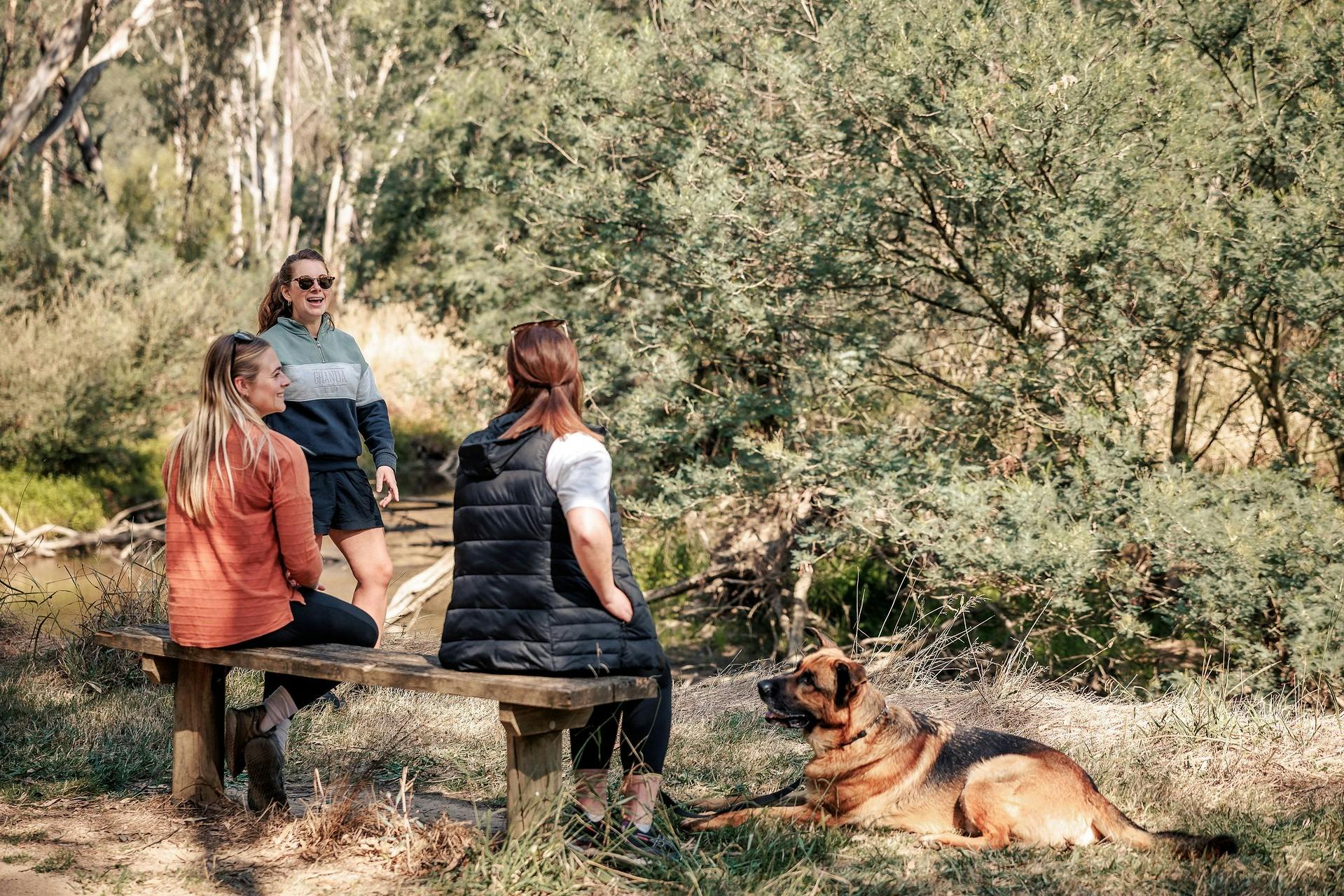 people sitting in nature and laughing with a dog