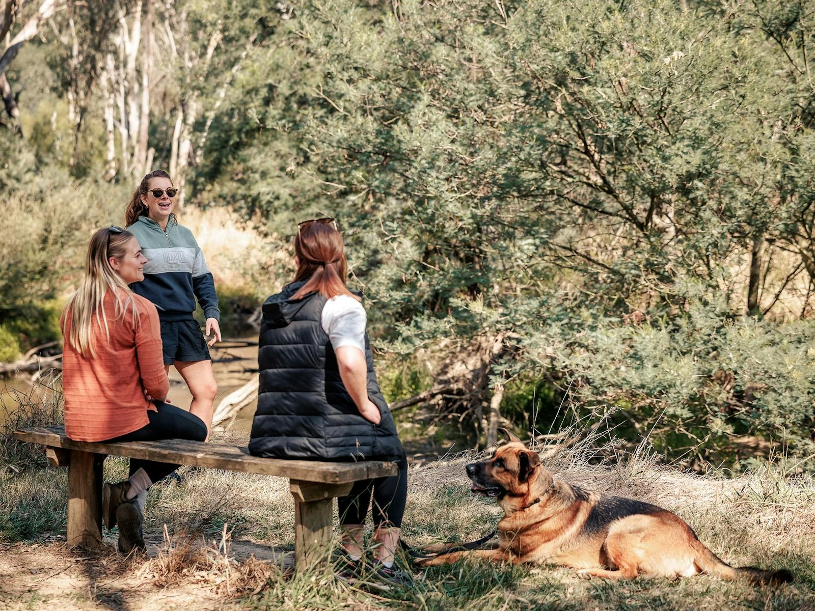 people sitting in nature and laughing with a dog