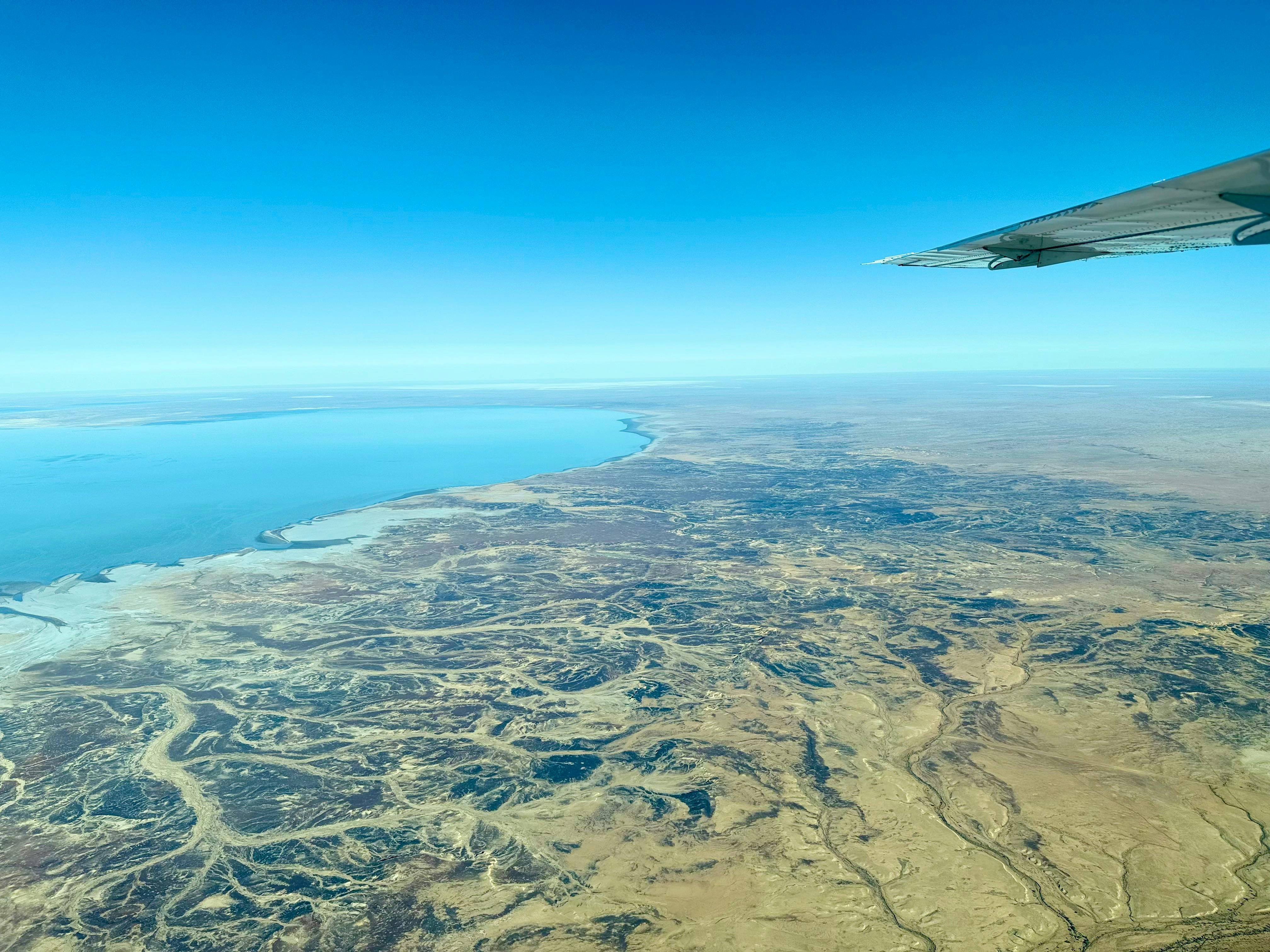 Aerial perspective of Lake Eyre with winding channels across the outback