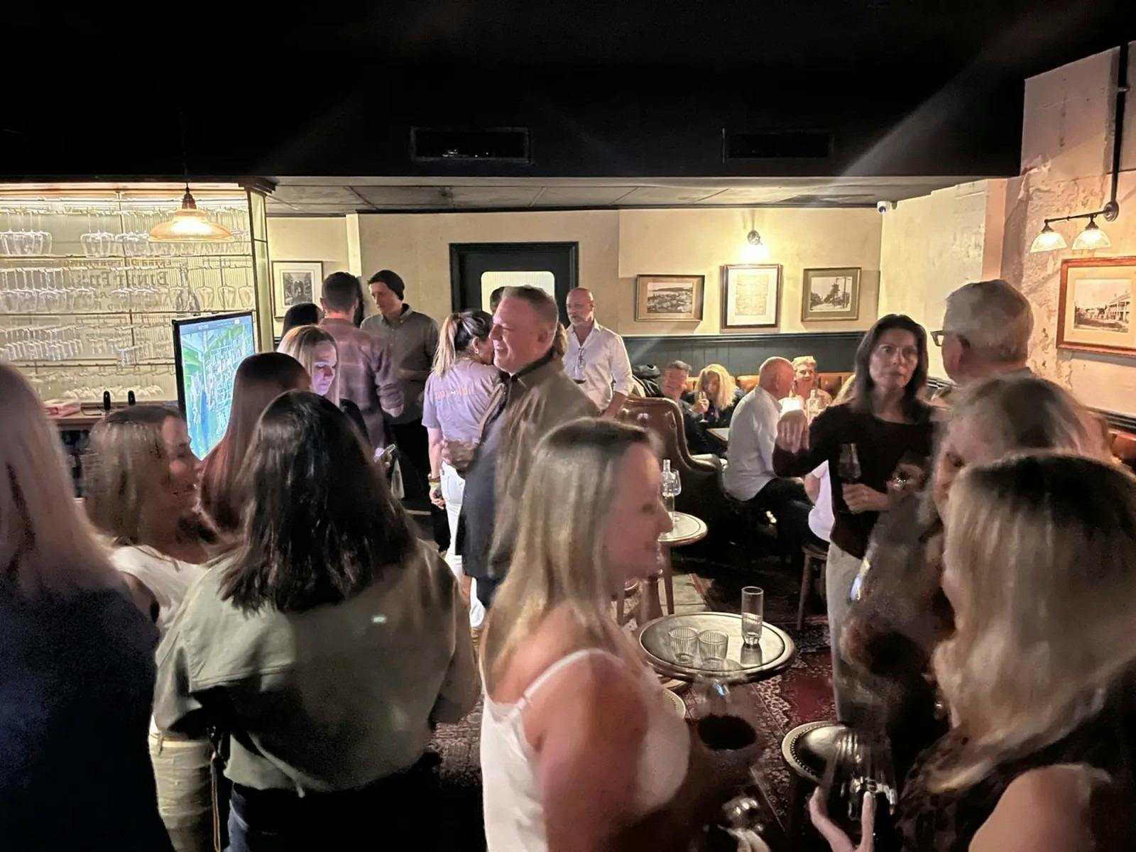 Guests mingling with drinks at a Date My Mate dating event in a warm timber-lined Manly bar