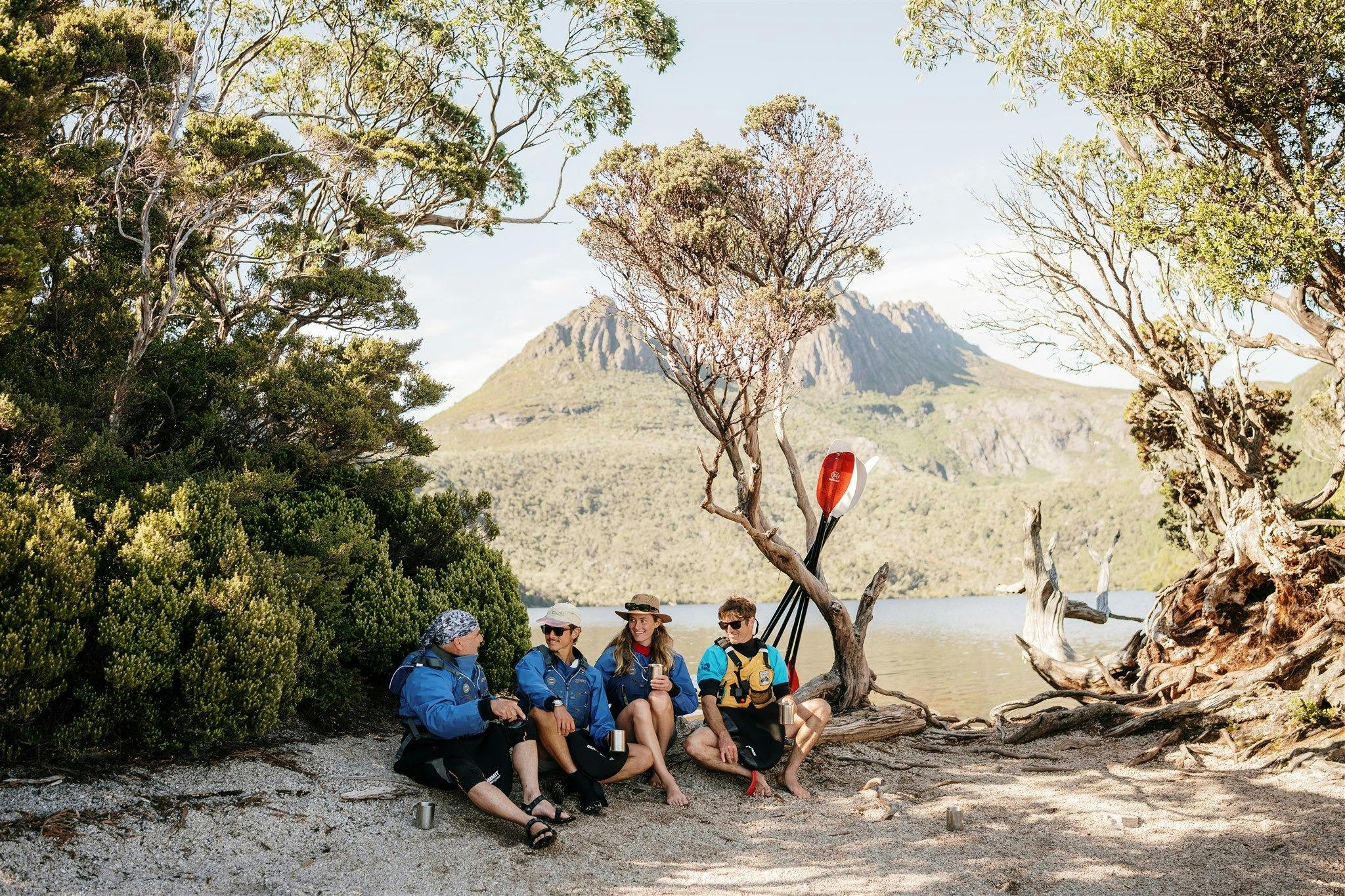 A group of kayakers sitting on a white beach next to Dove Lake