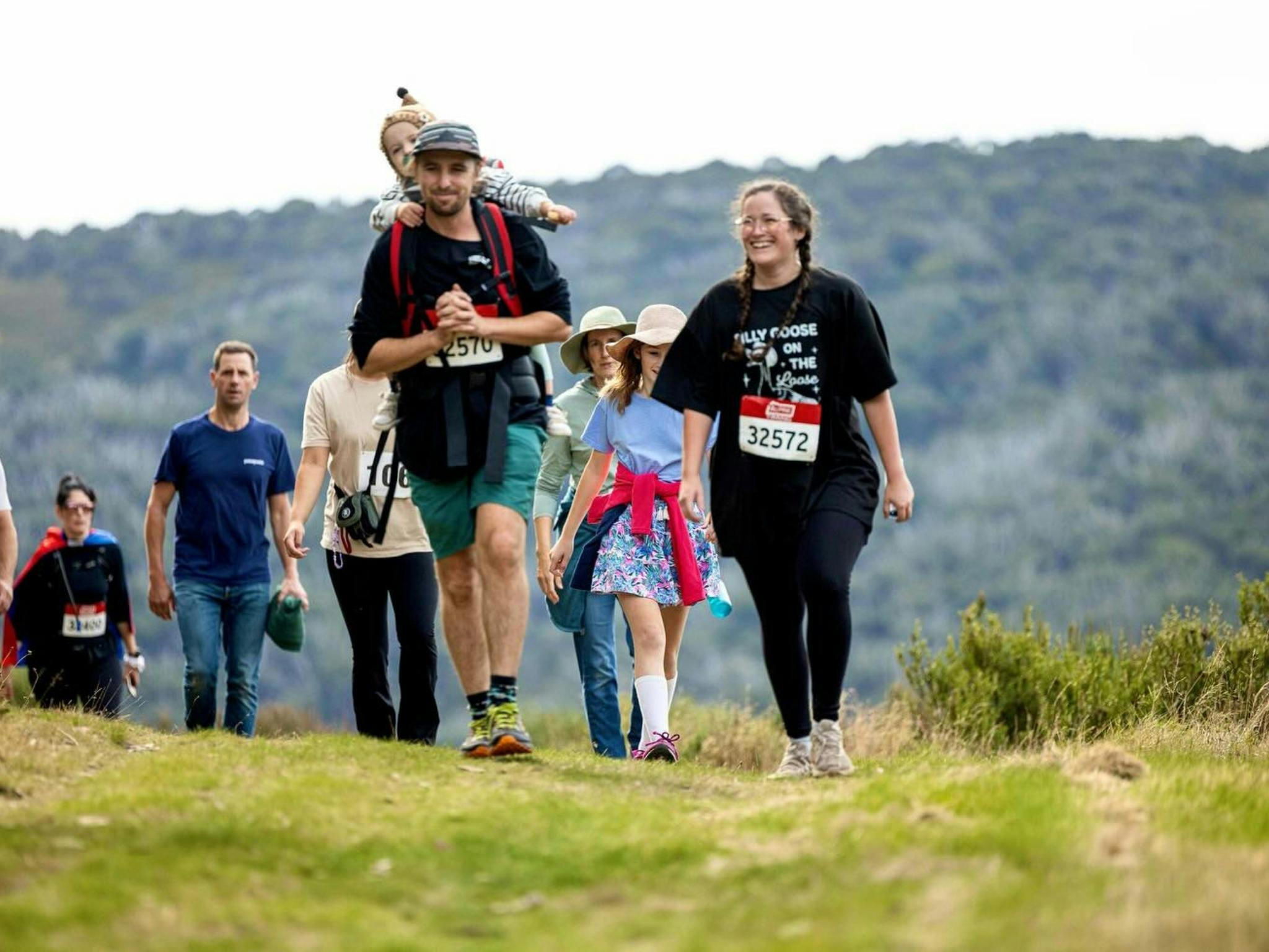 Family and crowd behind walking the trail with a baby carrier