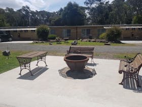 three benches facing toward a fire pit in an outdoor area