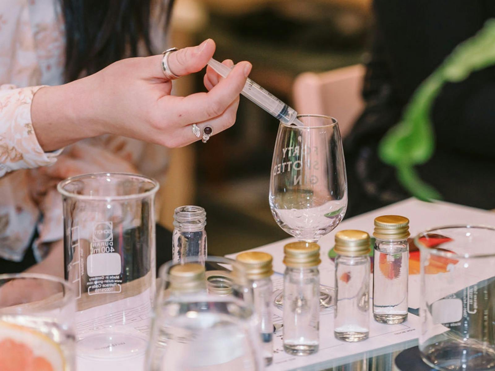 Bottles of botanicals being used to blend gin into a small glass