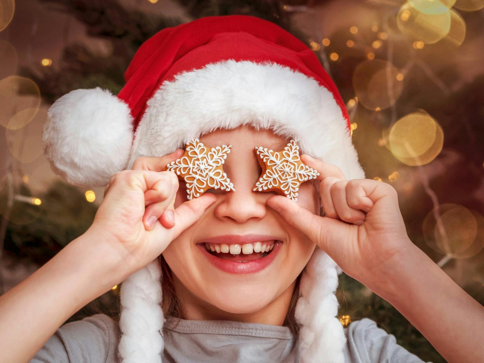 Christmas child with gingerbread star on his eyes, smiling