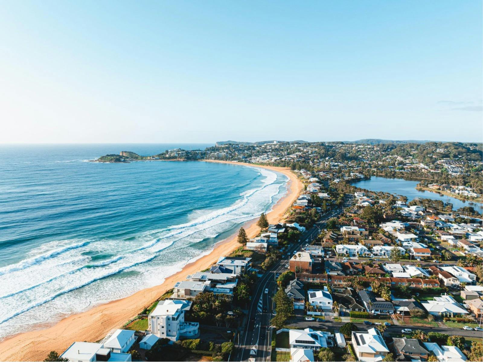 Aeriel view of Wamberal Beach, long sandy shoreline, ocean waves and surrounding residential area