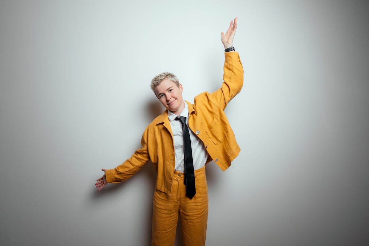Singer/songwriter Alex The Astronaut standing in a yellow suit with hands outstretched