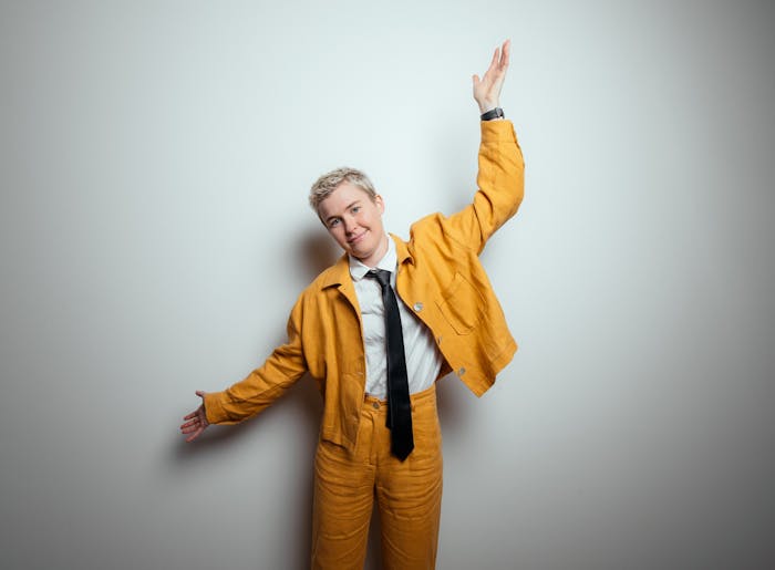 Singer/songwriter Alex The Astronaut standing in a yellow suit with hands outstretched