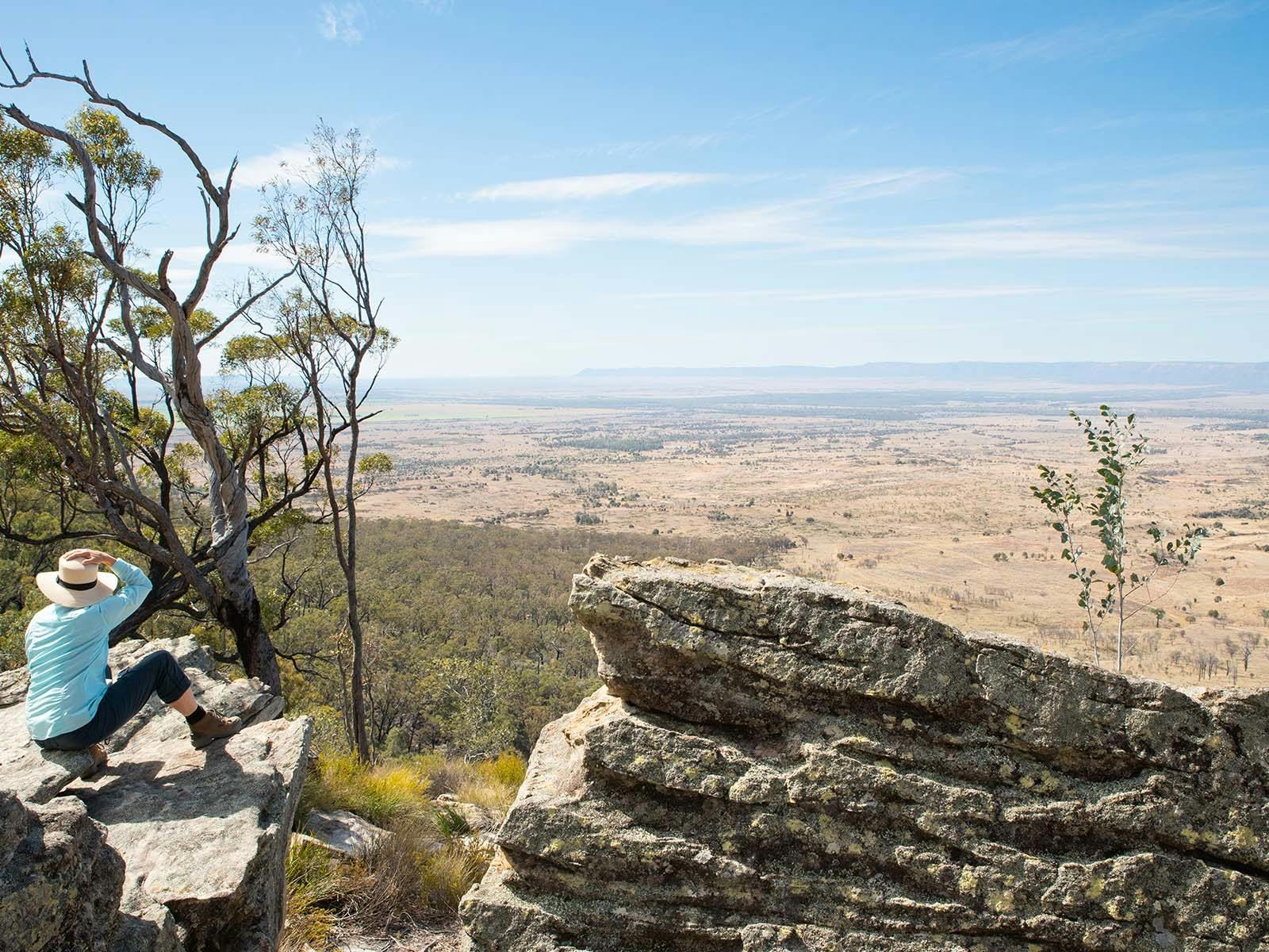 A guest sitting on a cliff looking out to the valley