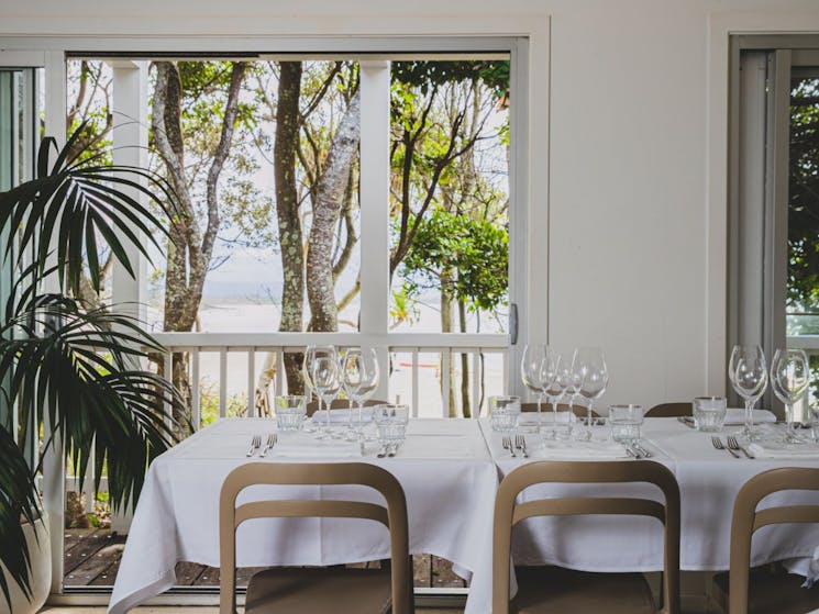 Inside the Beach Restaurant of dining room. Views out to trees with glimpses of the ocean.