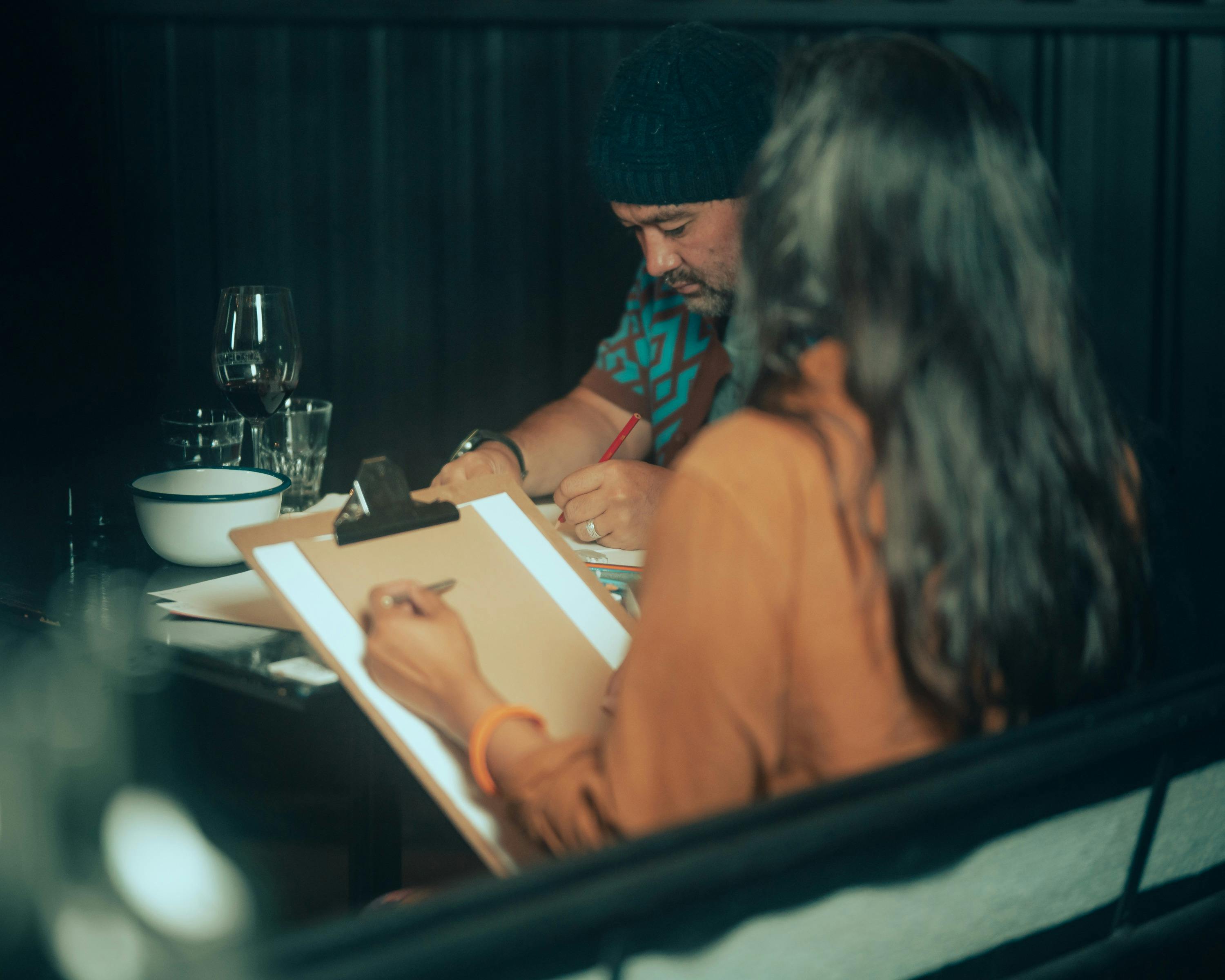 Two people drawing with wine on table