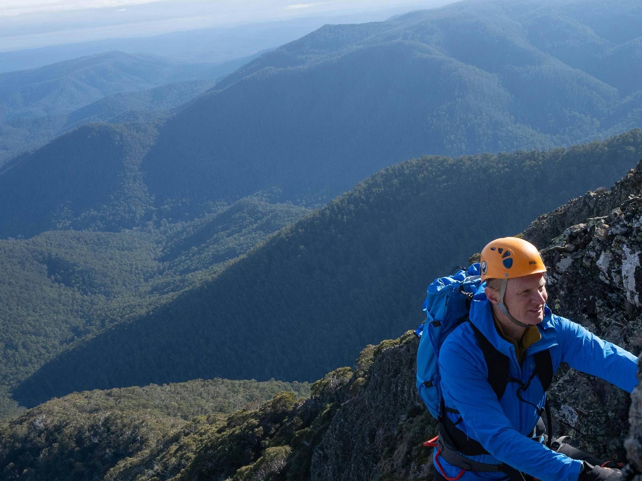 Climber in blue above the valley of bushland