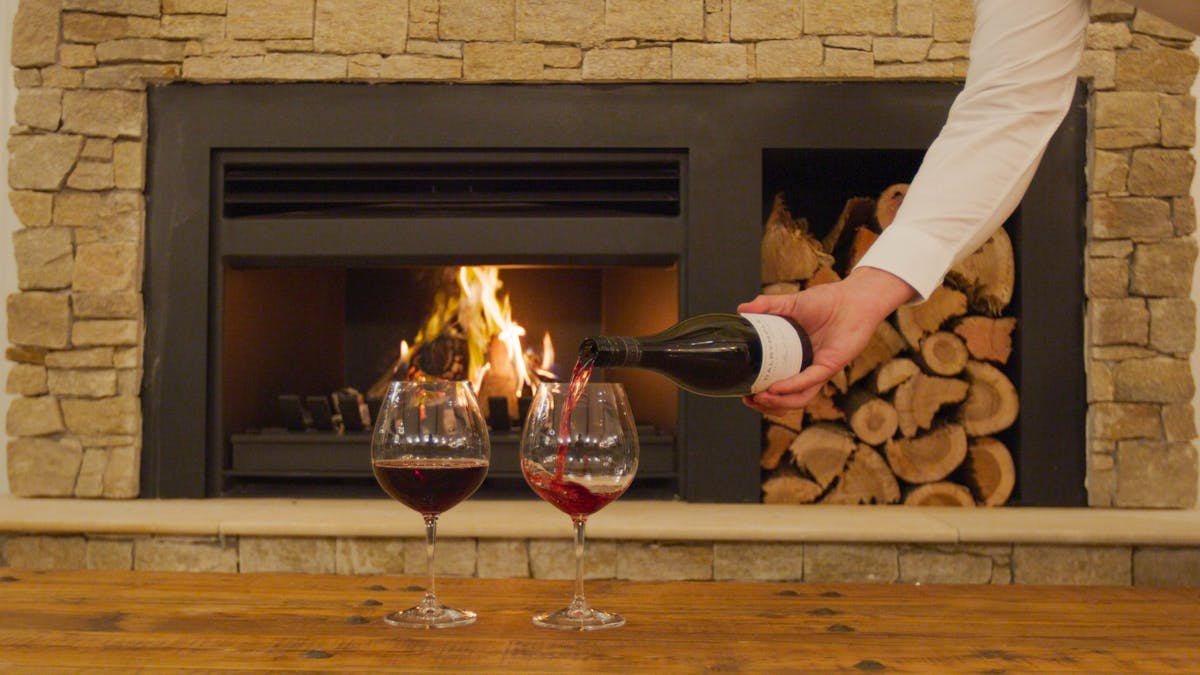 A waiter pours a glass of red in front of a roaring stone fireplace at Hazelwood Estate A waiter pours a glass of red in front of a roaring stone fireplace at Hazelwood Estate