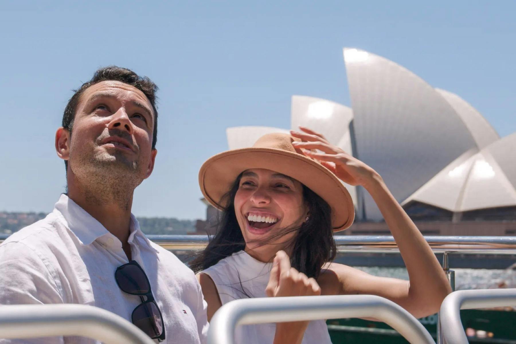 man and woman on sightseeing cruise with Sydney Opera House in background