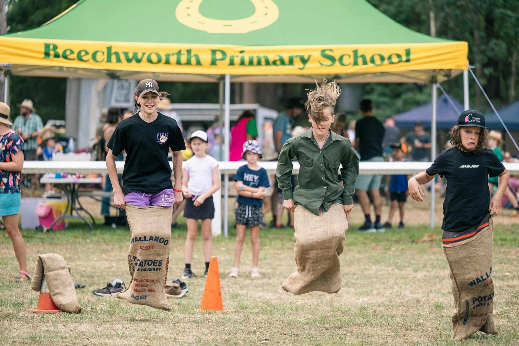 Children jumping high with hair flying  in a sack race at Spring Ditch 2023