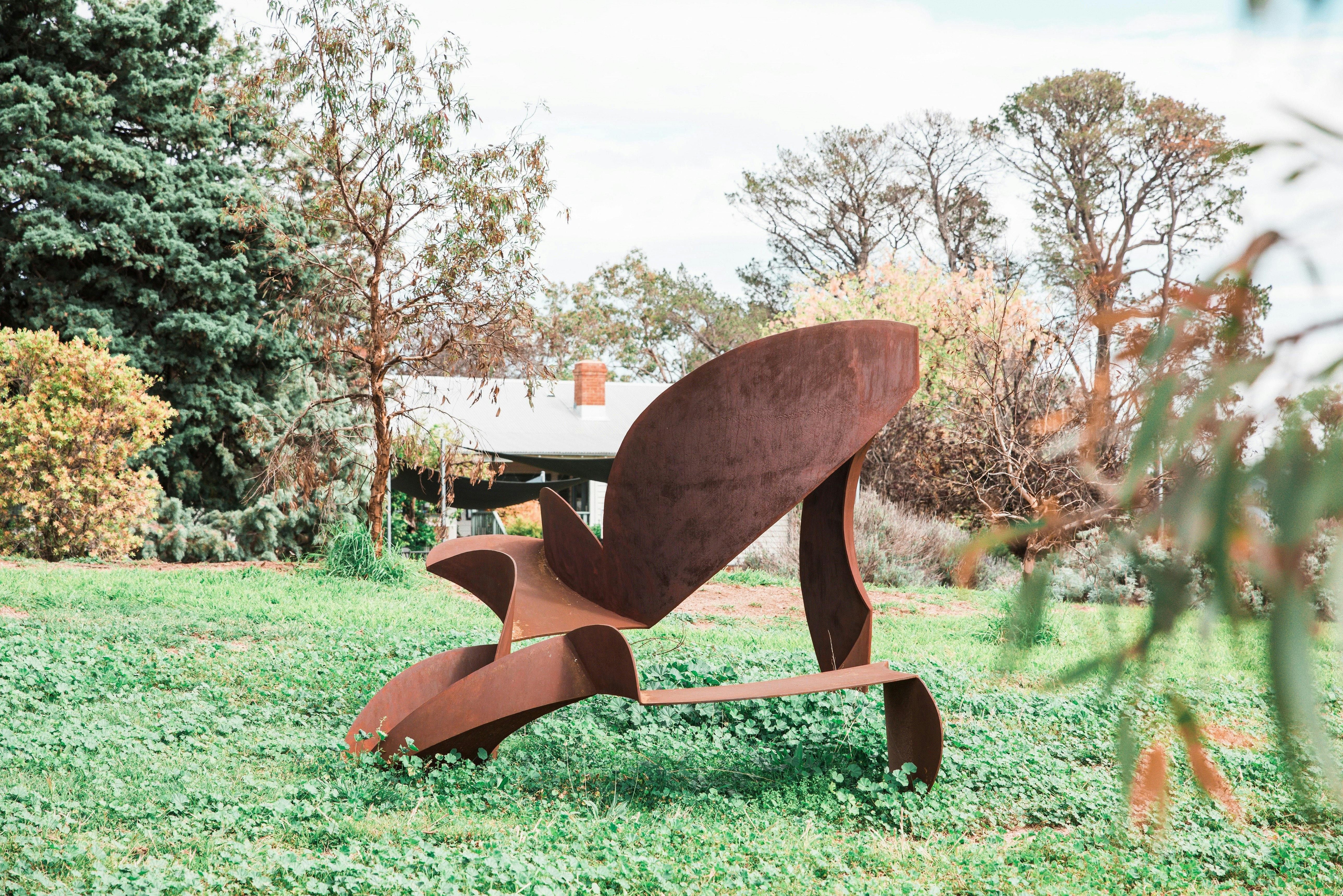 An abstract steel sculpture of geometric forms with a rusty patina in the garden.