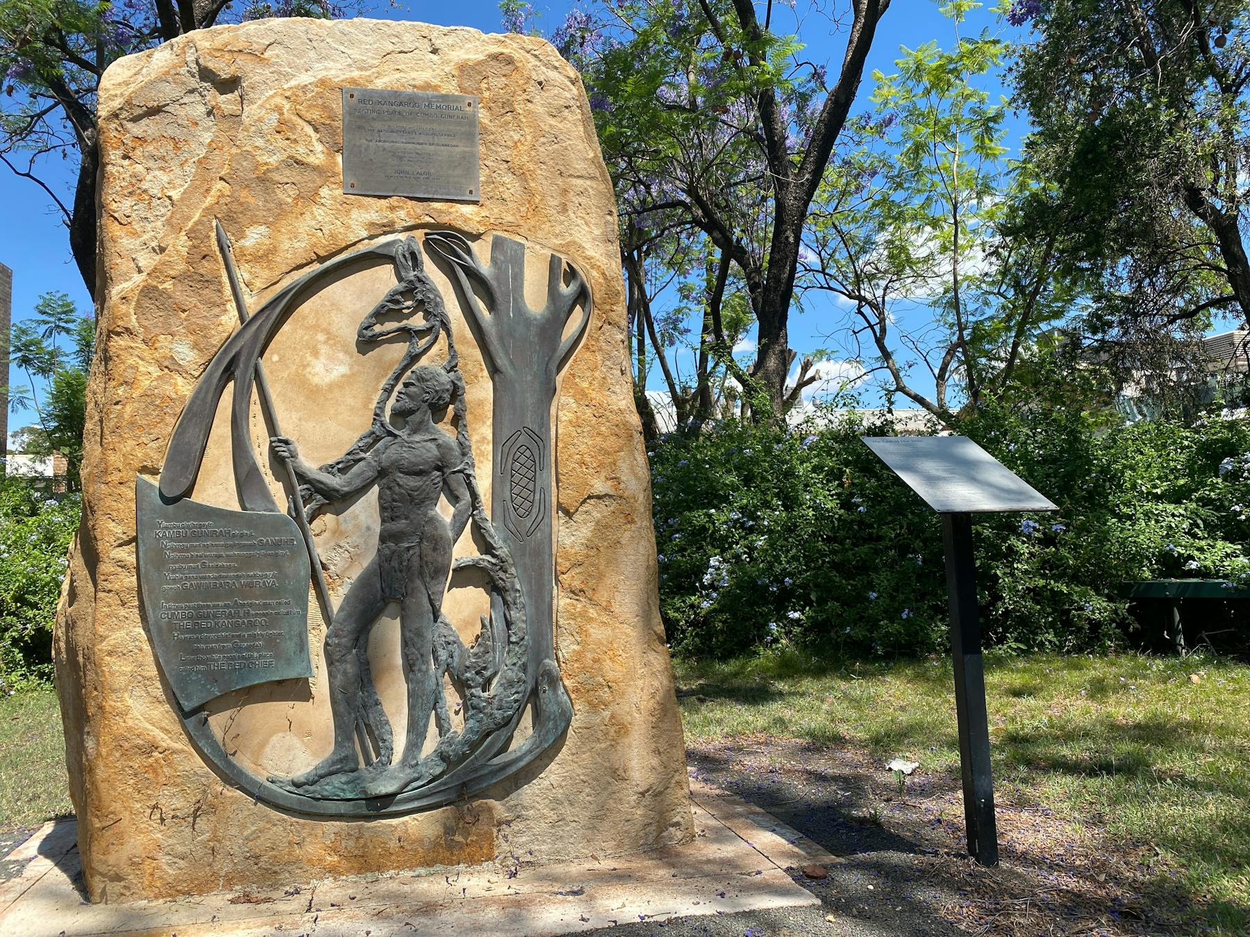 Sand stone tablet with bronze relief depicting an Aboriginal figure holding a spear
