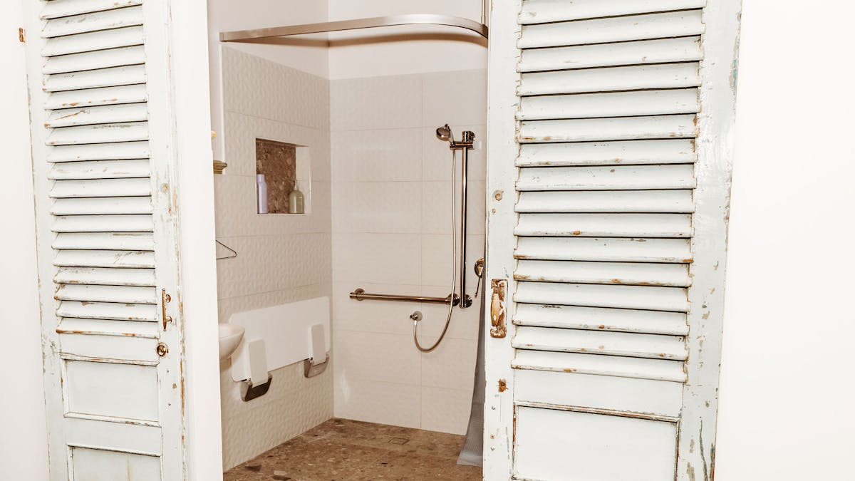 Re-purposed blue barn doors are opened looking through to accessible shower space.