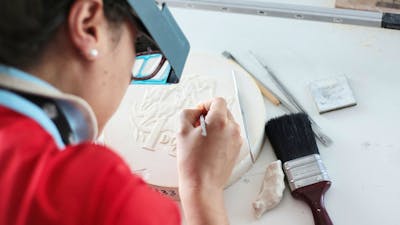 Image of a coin designer sculpting a design on plaster