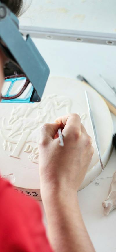 Image of a coin designer sculpting a design on plaster