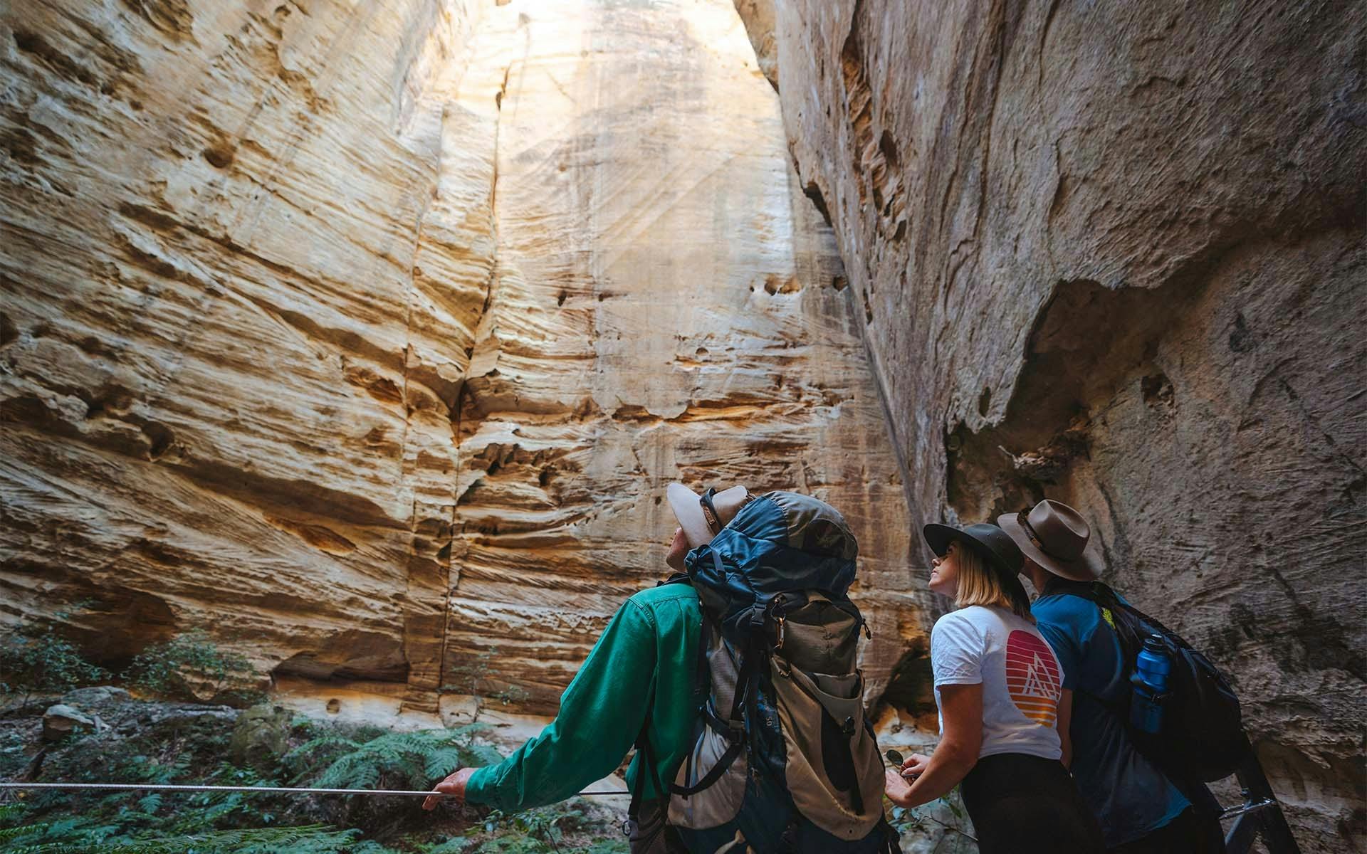 Three people looking up to an opening in a bright cave