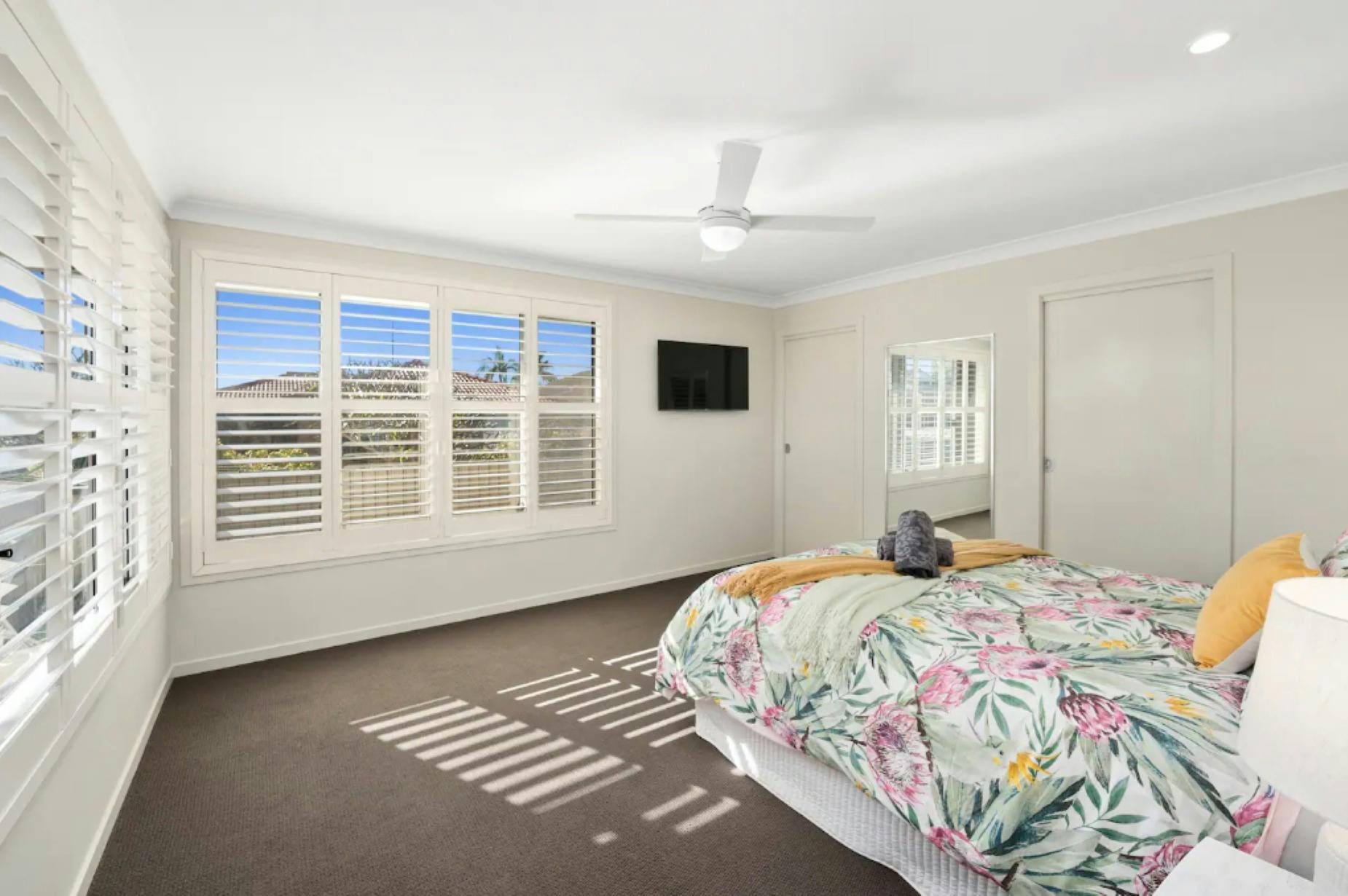 퀸 사이즈 침대 목재 셔터 천장 선풍기 및 TV가 있는 마스터 침실