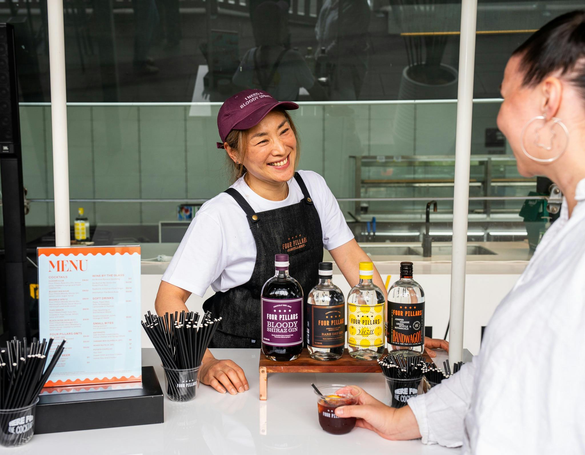 A smiling bar tender taking to a customer at the bar