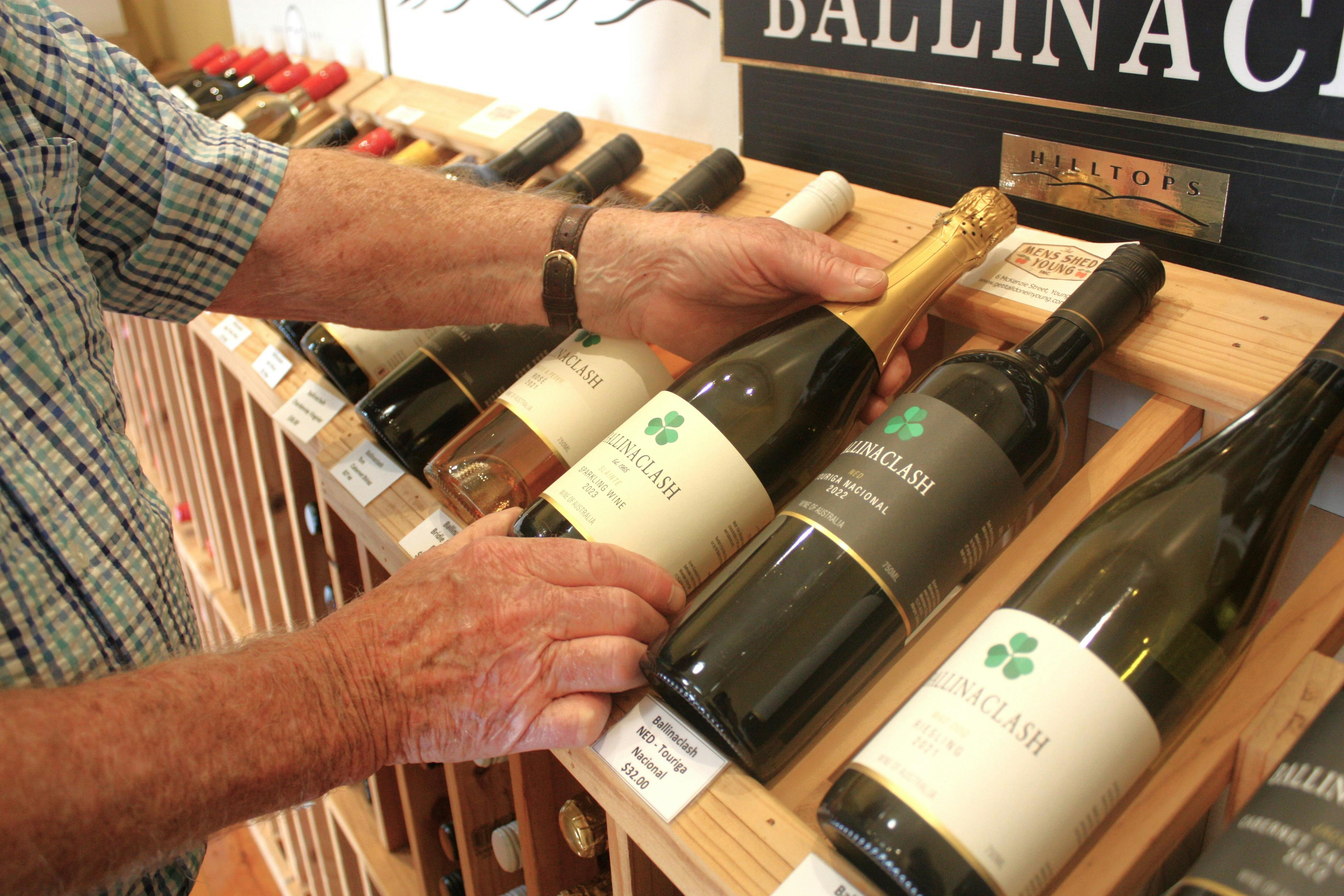 Man's hands delicately picking up a bottle of sparkling wine.