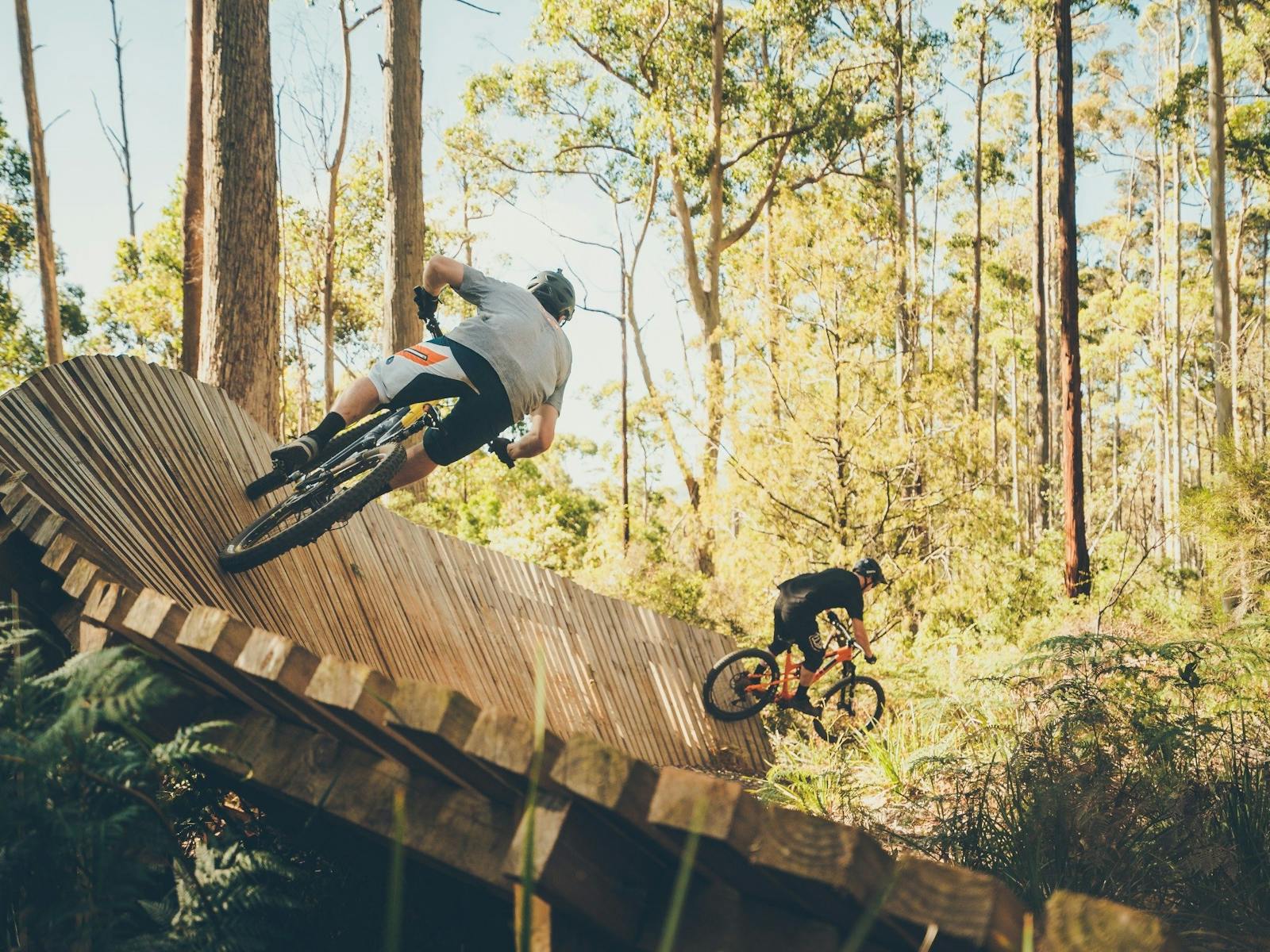 men riding mountain bikes on wooden obsticles