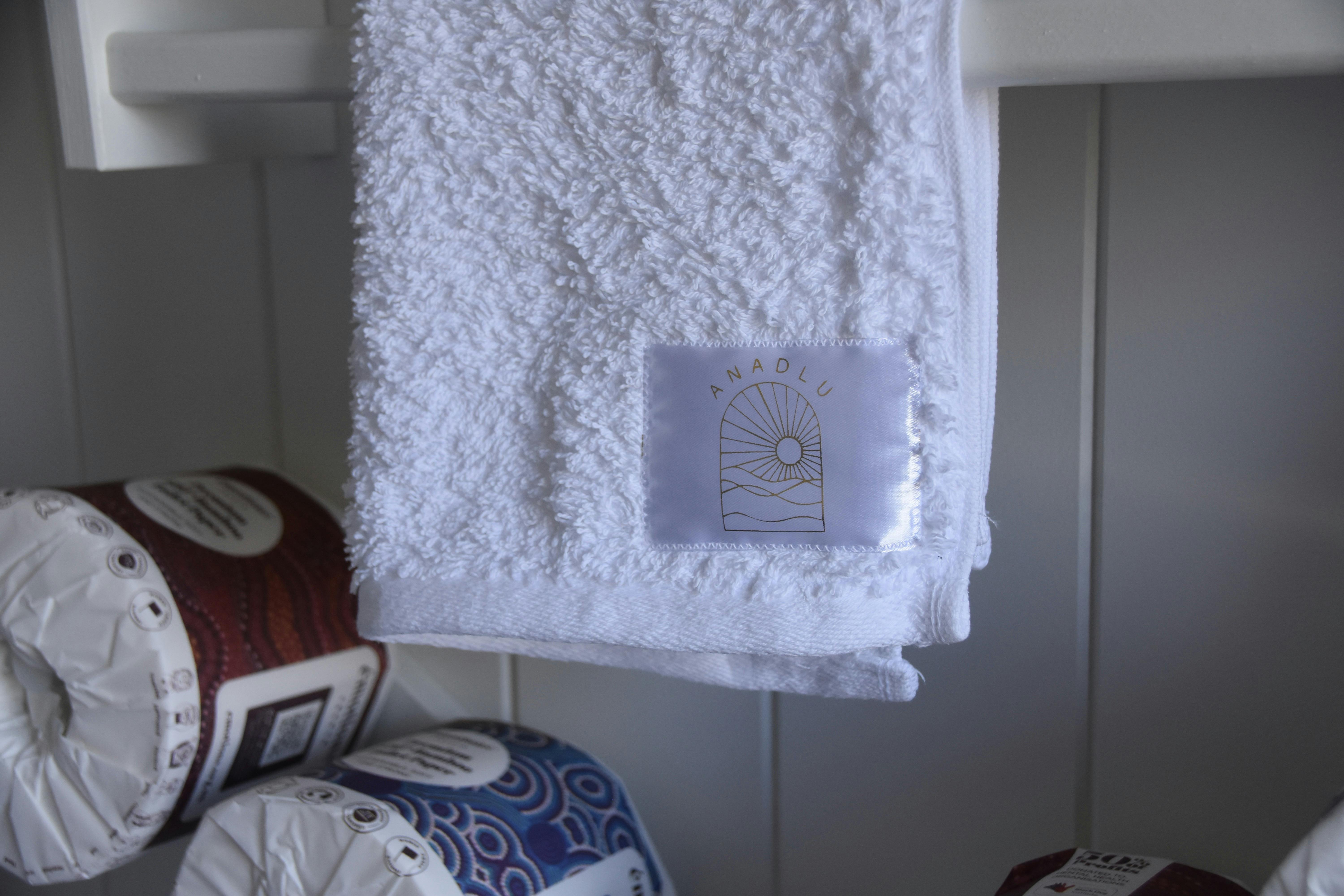 Close-up of white Anadlu-branded towels neatly displayed in the bathroom