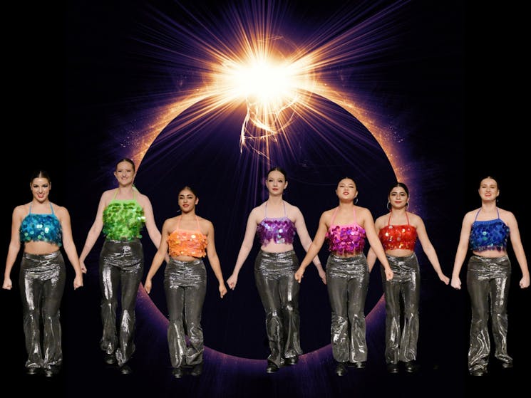 Seven dancers in front of a solar eclipse