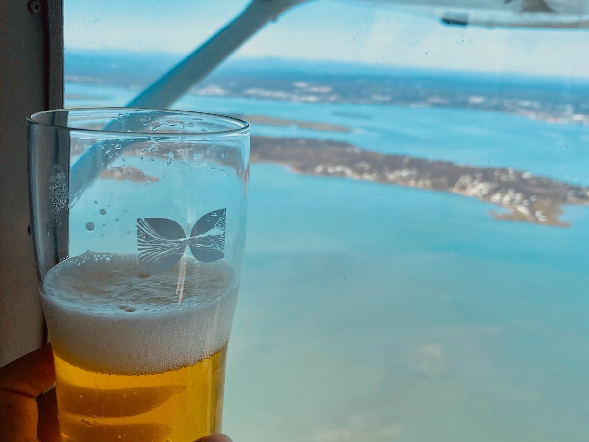A beer beside a window looking from an airplane