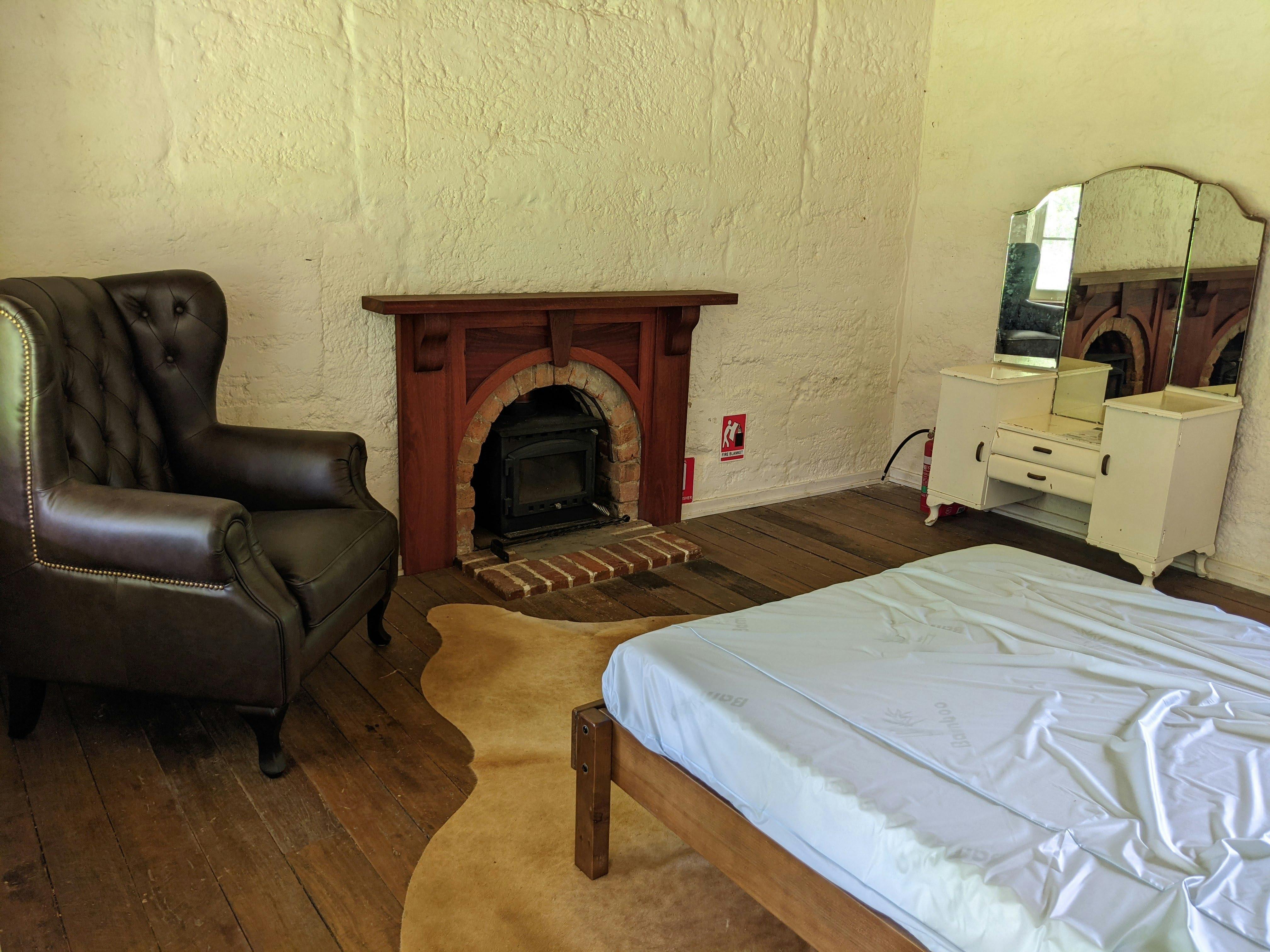 Bedroom with double bed, fireplace, wingback chair and vintage dressing table with mirrors