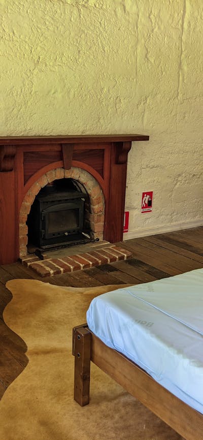 Bedroom with double bed, fireplace, wingback chair and vintage dressing table with mirrors
